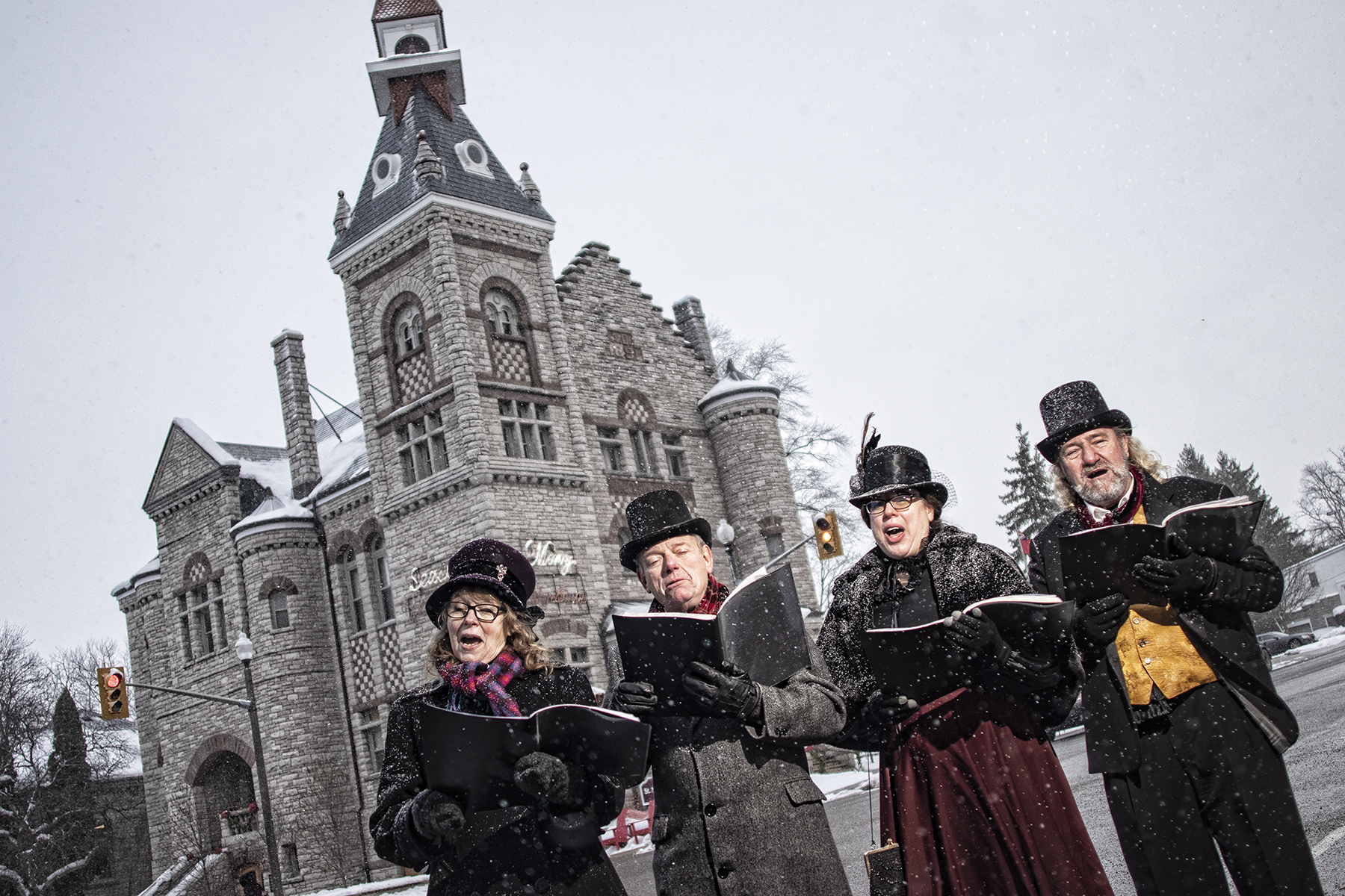Carolers singing putside in the snow in fron of Twn Hall