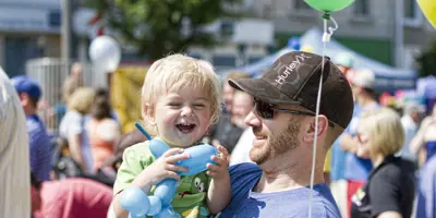 Person holding happy child at street festival